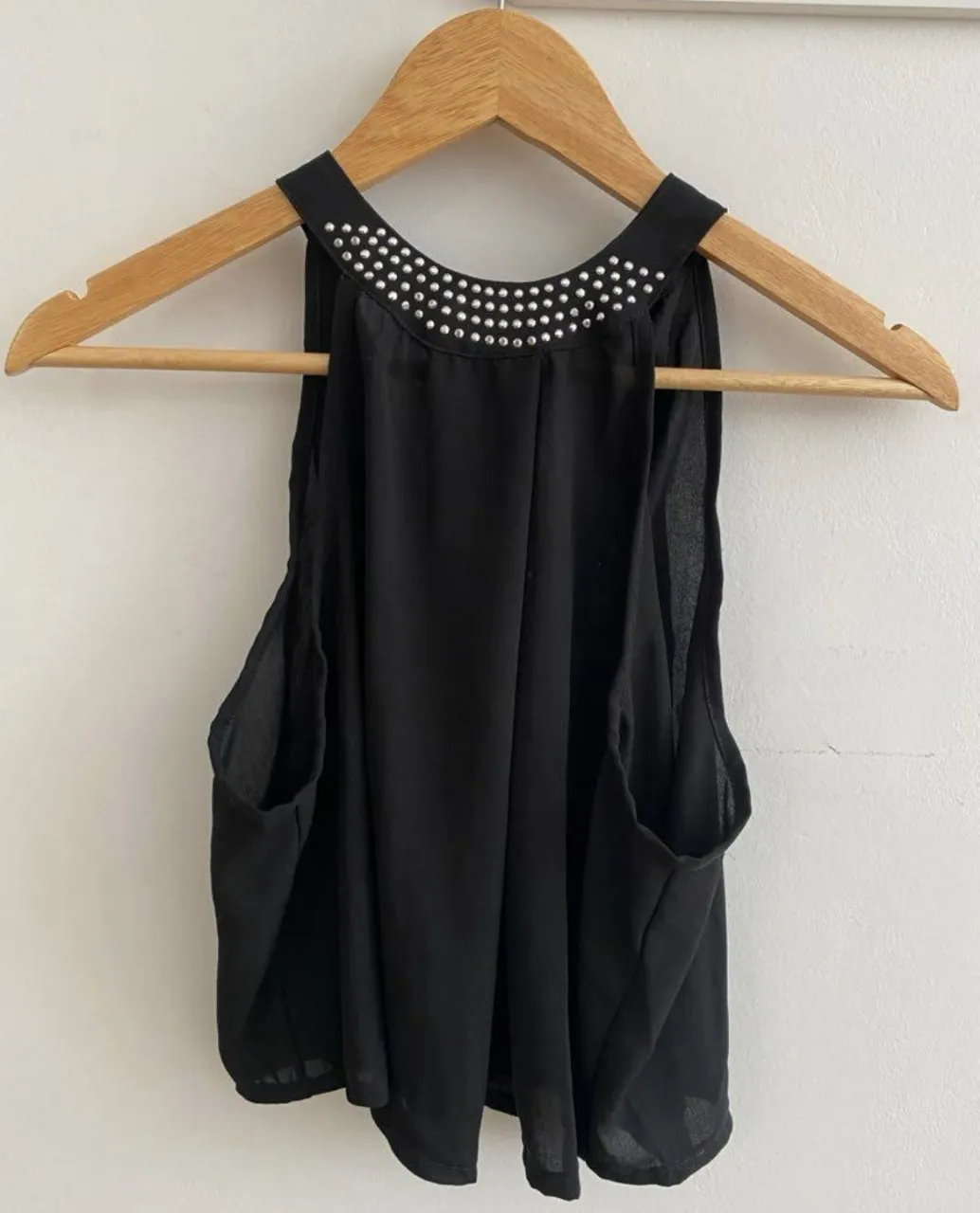 Blusa negra con detalles de strass en el cuello. Ideal para una salida o evento especial. Diseño elegante y sofisticado.