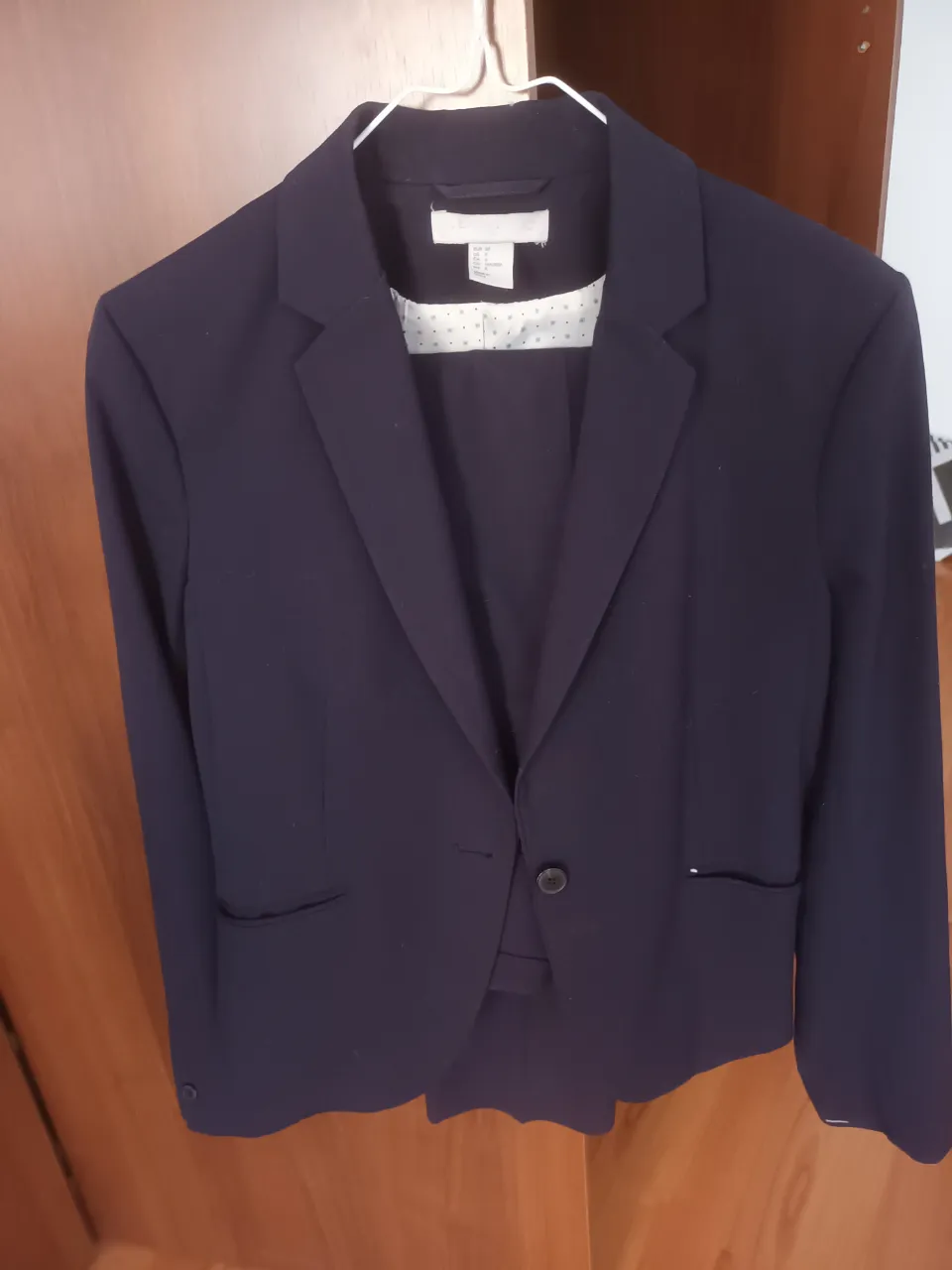 Traje de blazer y pantalón de vestir azul marino, ideal para un look formal o de trabajo. Blazer con un botón y bolsillos, pantalón a juego.