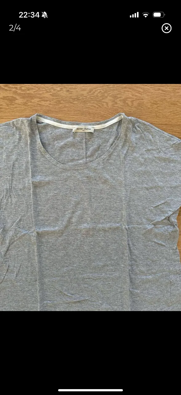 Remera de manga corta gris, con cuello redondo y detalle blanco en el borde. Ideal para un look casual y cómodo.