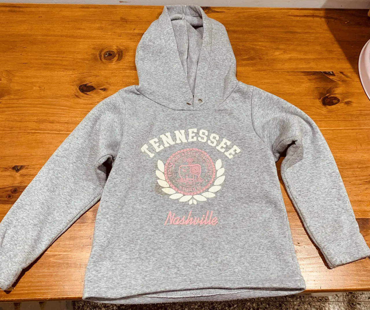 Buzo canguro gris con capucha para niña. Estampado "Tennessee" y "Nashville" en rosa. Ideal para un look casual y cómodo.