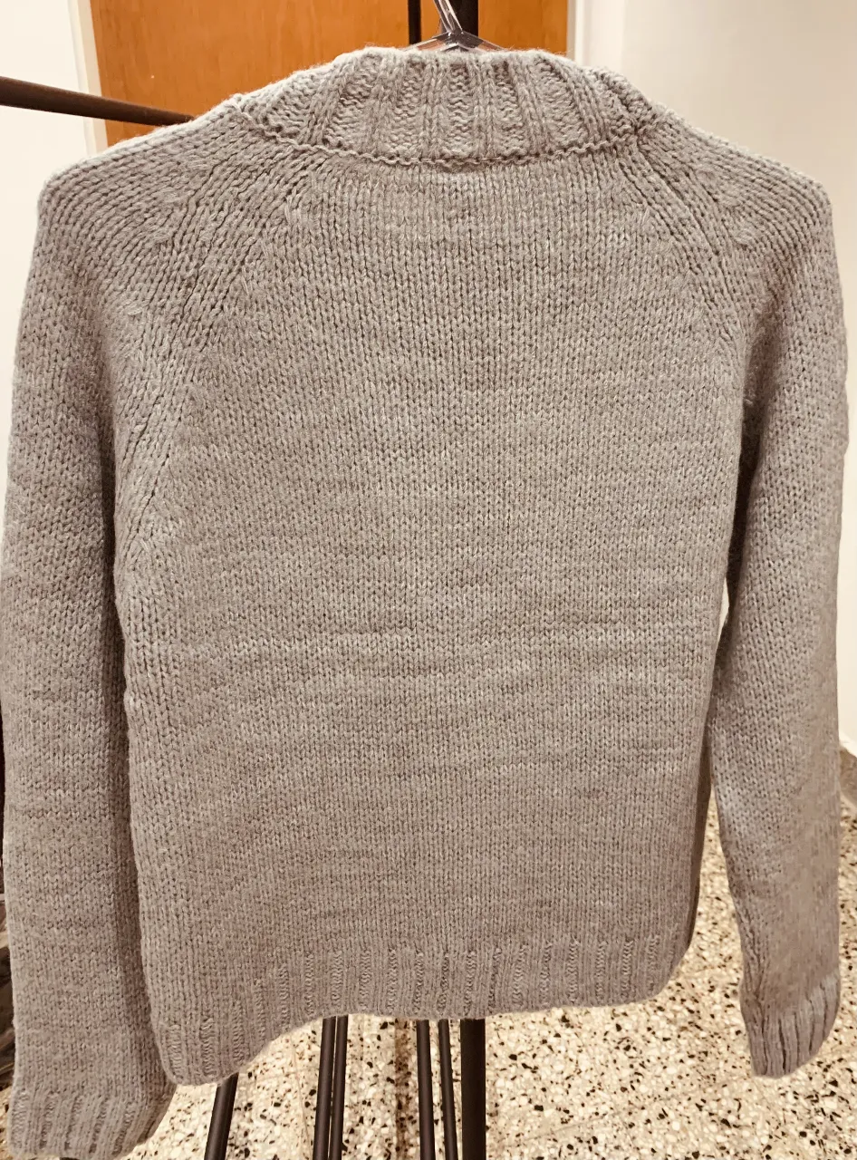 Sweater de lana gris con diseño de águila bordado en el frente. Cuello redondo y mangas largas. Ideal para un look casual y abrigado.
