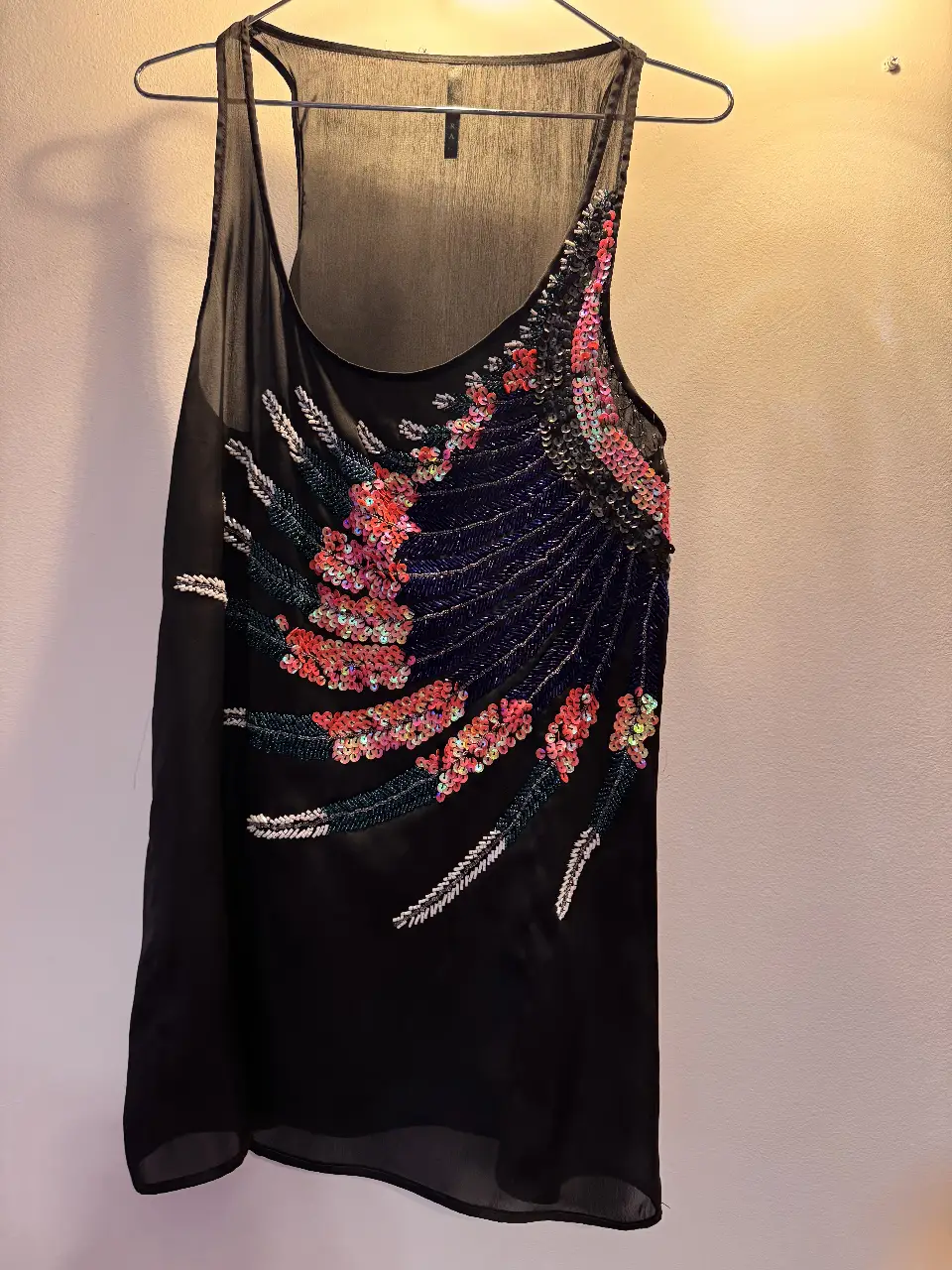 Musculosa negra con apliques de lentejuelas y bordados en tonos rojos, rosas y azules. Ideal para fiestas y eventos especiales.
