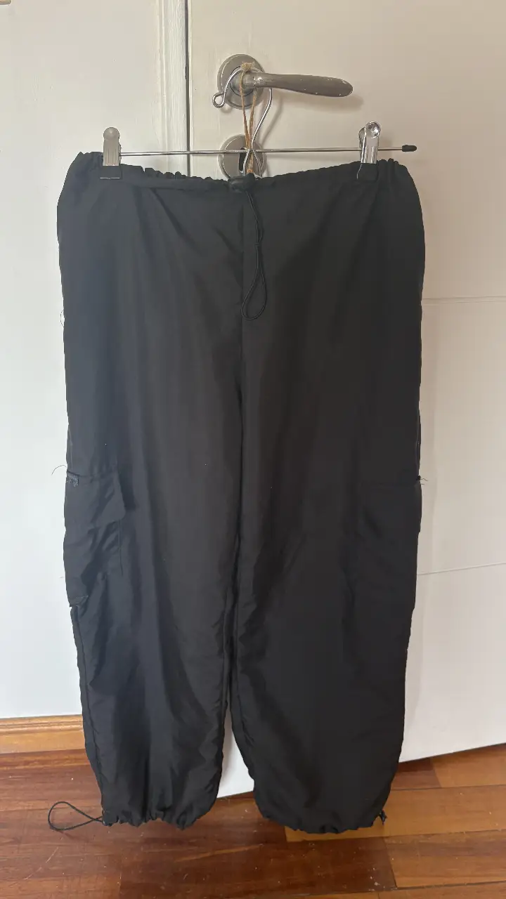 Pantalón cargo negro, con bolsillos laterales y ajuste en los tobillos. Ideal para un look casual y cómodo. parachute 