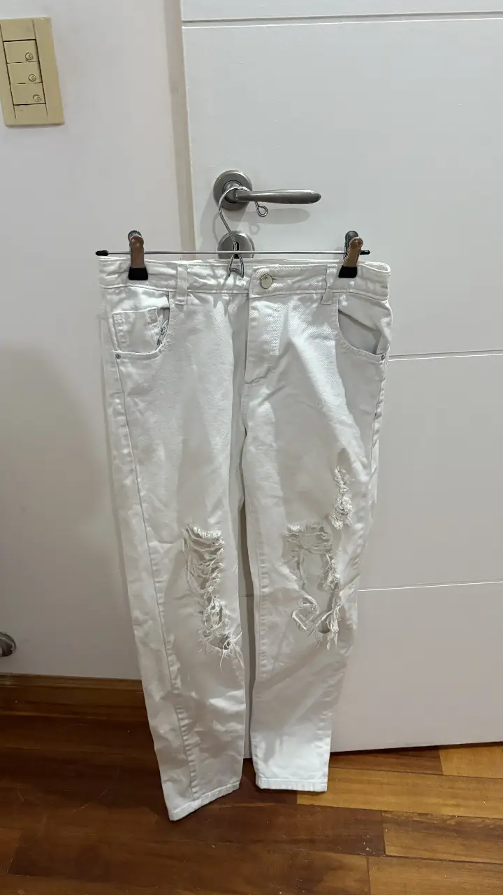 Jeans de mujer blancos con roturas en las rodillas. Tiro medio, corte recto y diseño moderno. Ideal para un look casual y canchero pantalón Muaa equivale a un 38.