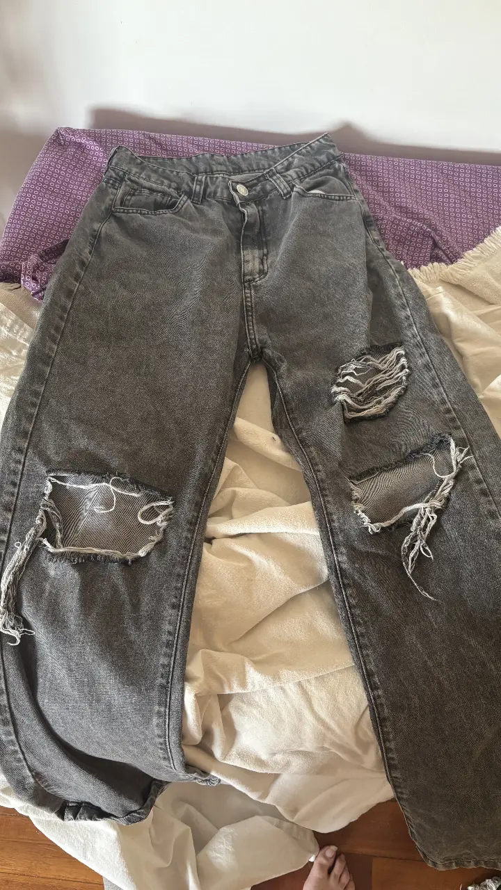 Jeans grises con roturas en las rodillas, tiro medio y corte recto. Un clásico canchero para un look casual y moderno.