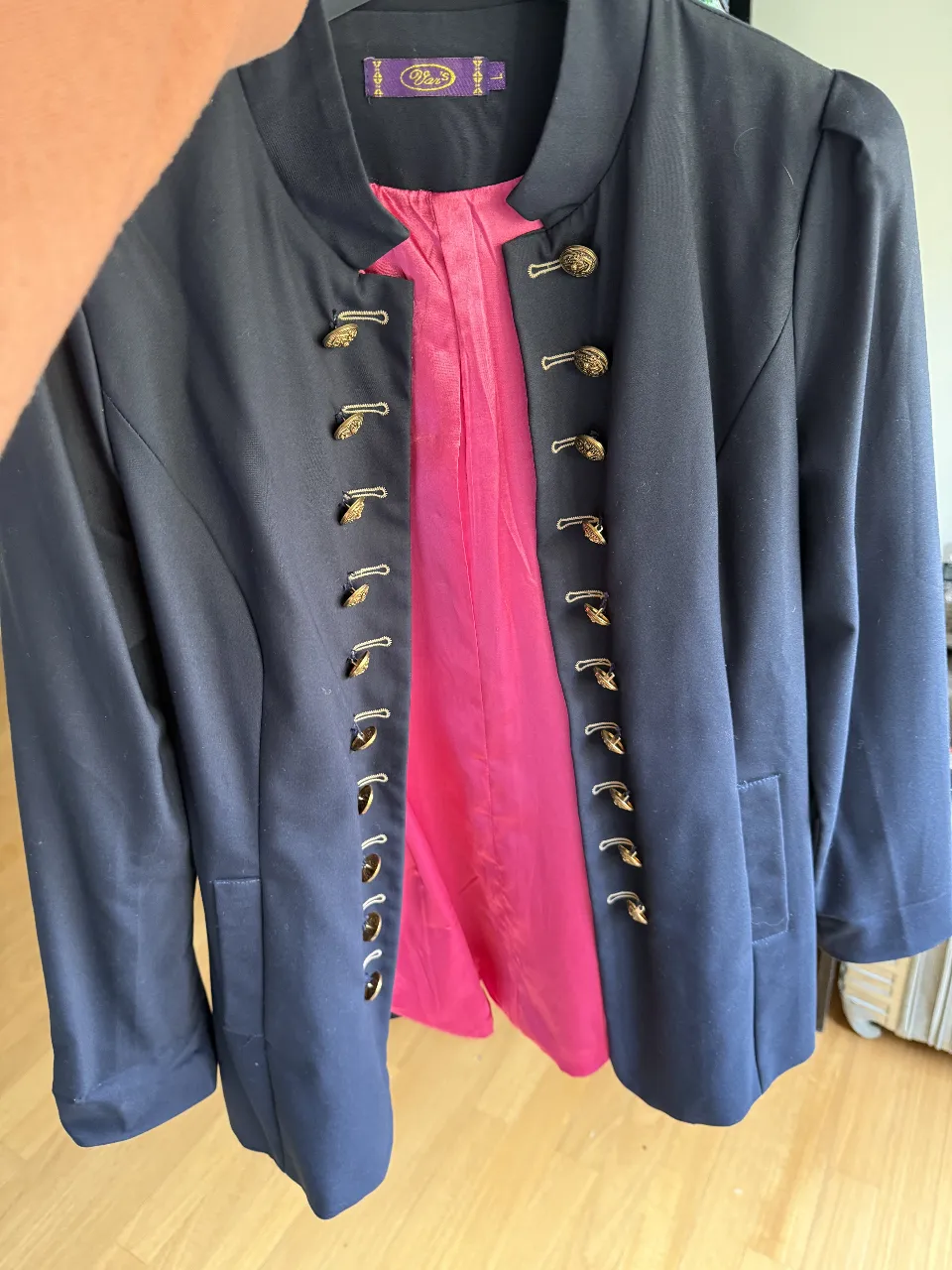 Elegante blazer azul marino con detalles dorados y forro rosa. Ideal para un look sofisticado y con estilo.