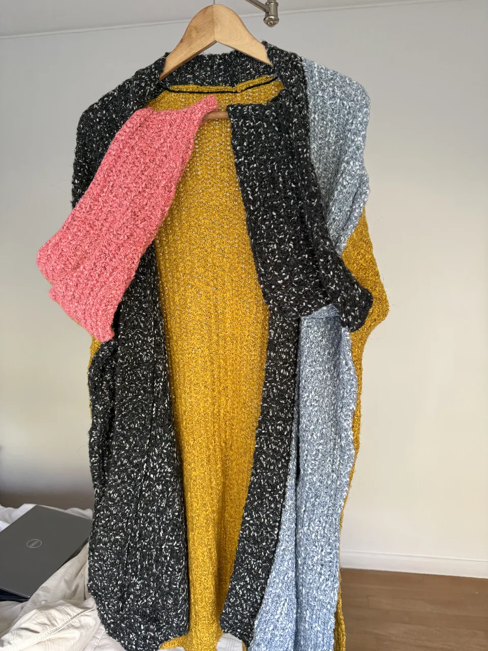 Cardigan largo de tejido grueso con bloques de color. Posee mangas en color rosa y gris, y un cuerpo amarillo. Ideal para un look casual y abrigado.