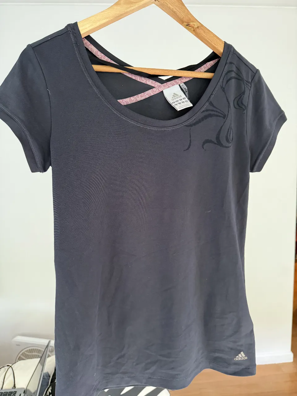 Remera deportiva Adidas Clima, color gris oscuro, con detalles en rosa en la parte trasera del cuello. Ideal para entrenamientos.