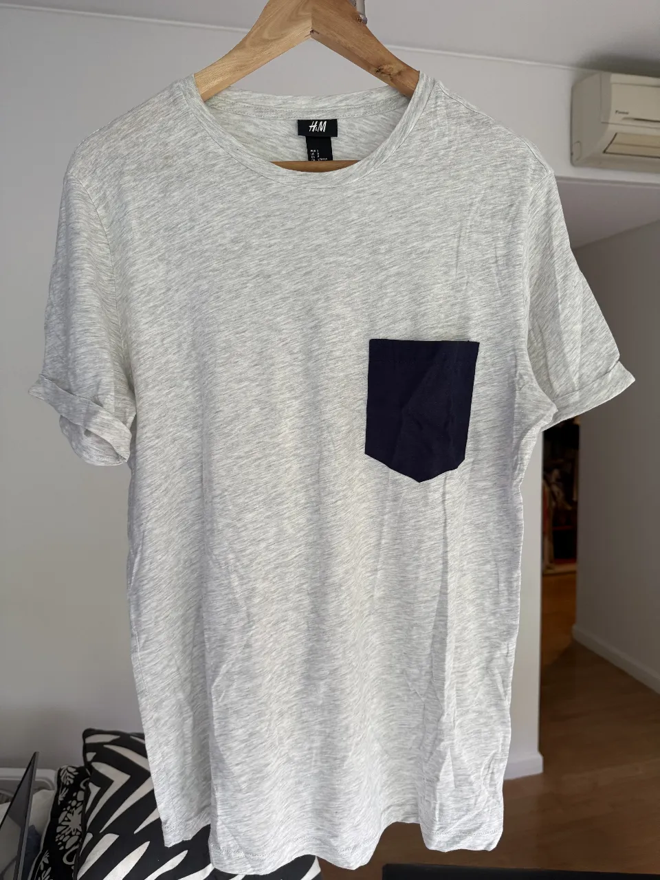 Remera de hombre gris con bolsillo azul. Talle S de H&M. Ideal para un look casual y cómodo.