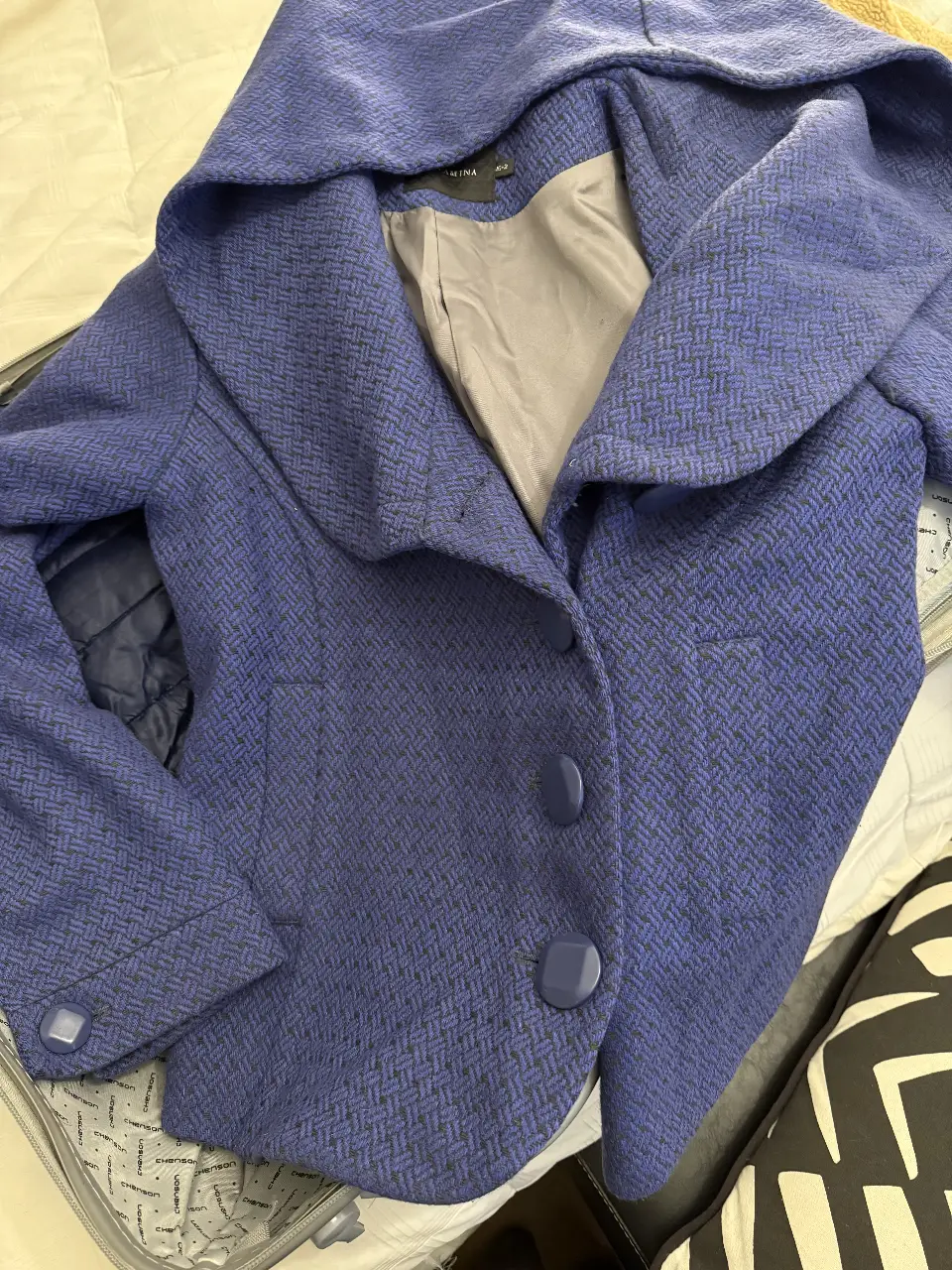 sacon corto azul claro con capucha, de tela con textura. Posee botones grandes y un diseño elegante. Ideal para el invierno.