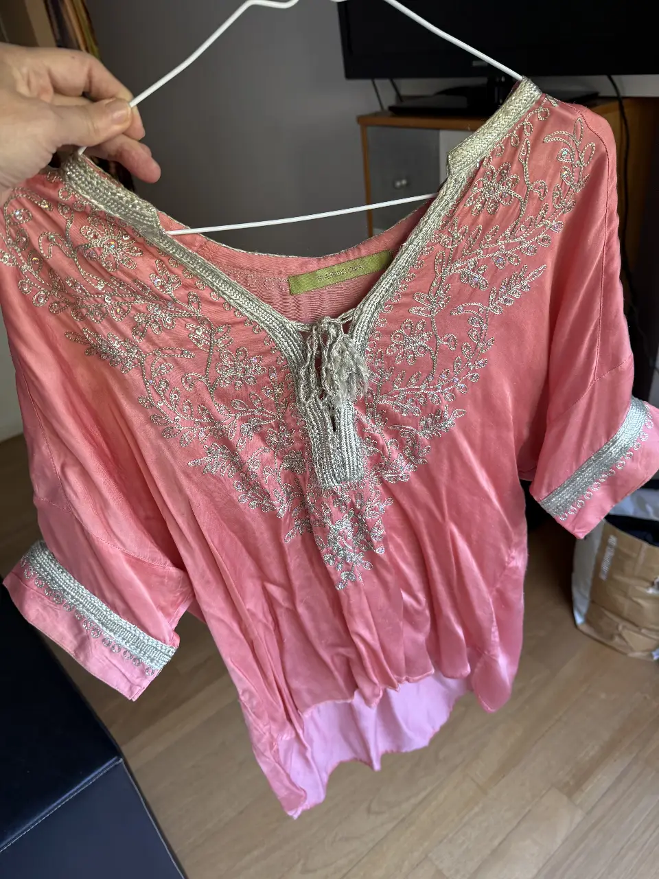 Blusa de seda rosa con detalles bordados en plateado y flecos en el cuello. Ideal para un look canchero y sofisticado.