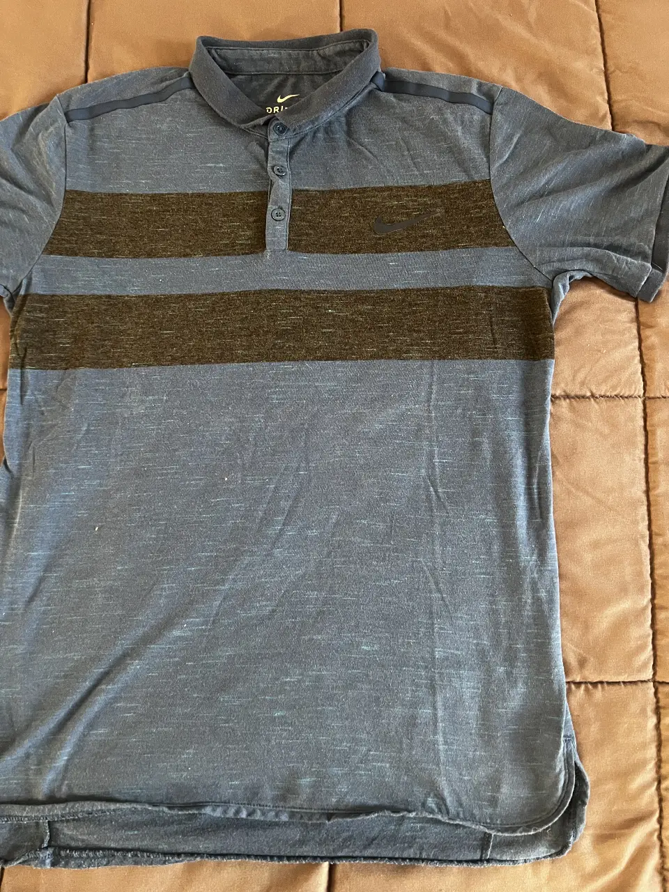 Remera deportiva de hombre, con cuello polo y diseño a rayas horizontales en tonos azul y marrón. Ideal para actividades deportivas o uso casual.