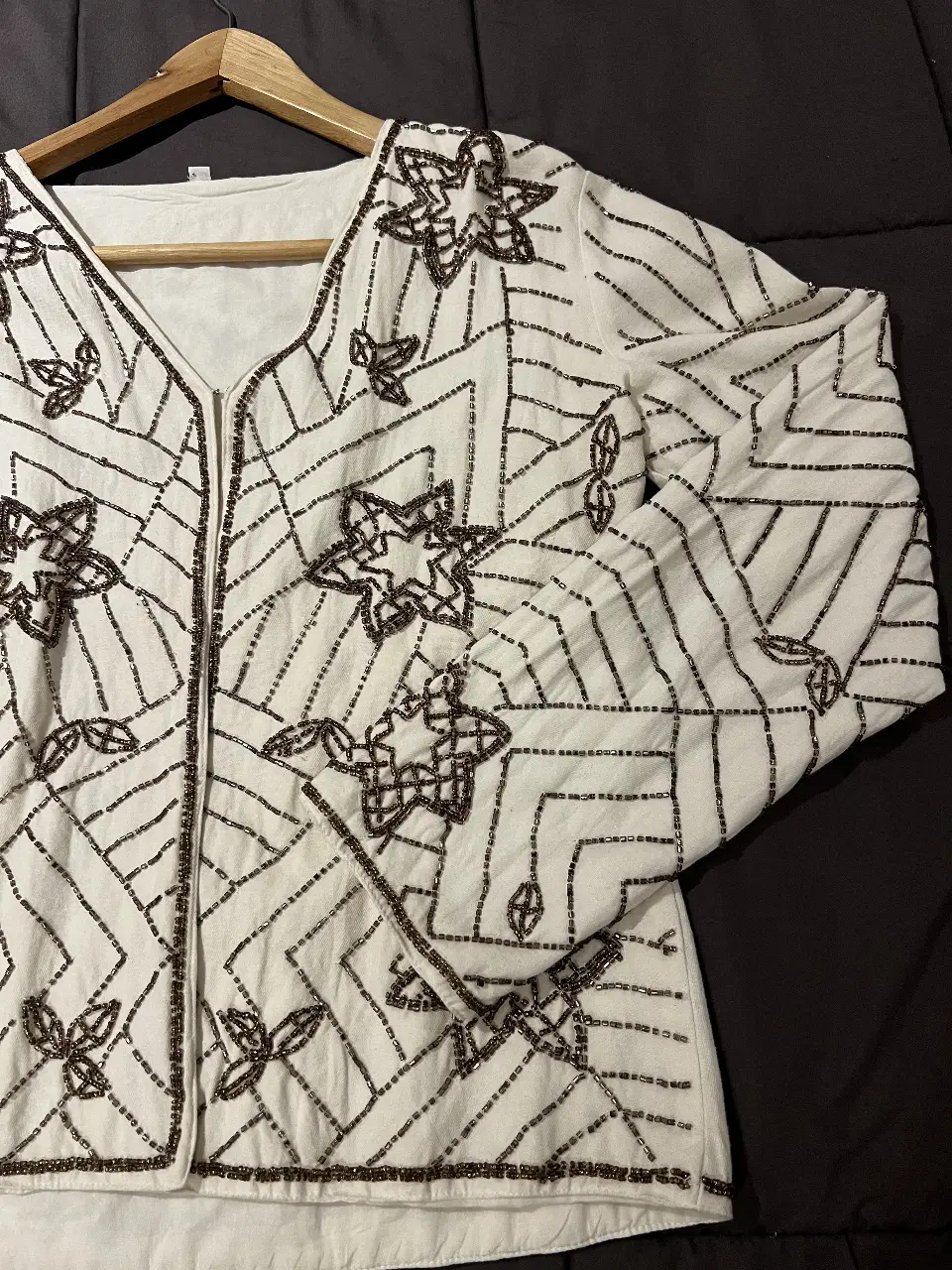 Blusa blanca con detalles bordados en color marrón. Diseño con cuello en V y cierre frontal. Ideal para un look bohemio y elegante.