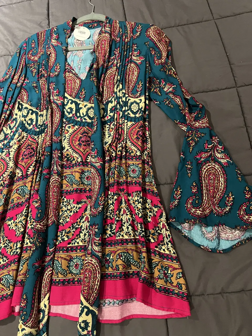 Vestido largo de estilo boho con estampado paisley en tonos turquesa, rosa y amarillo. Mangas acampanadas y corte holgado, ideal para un look bohemio y cómodo.