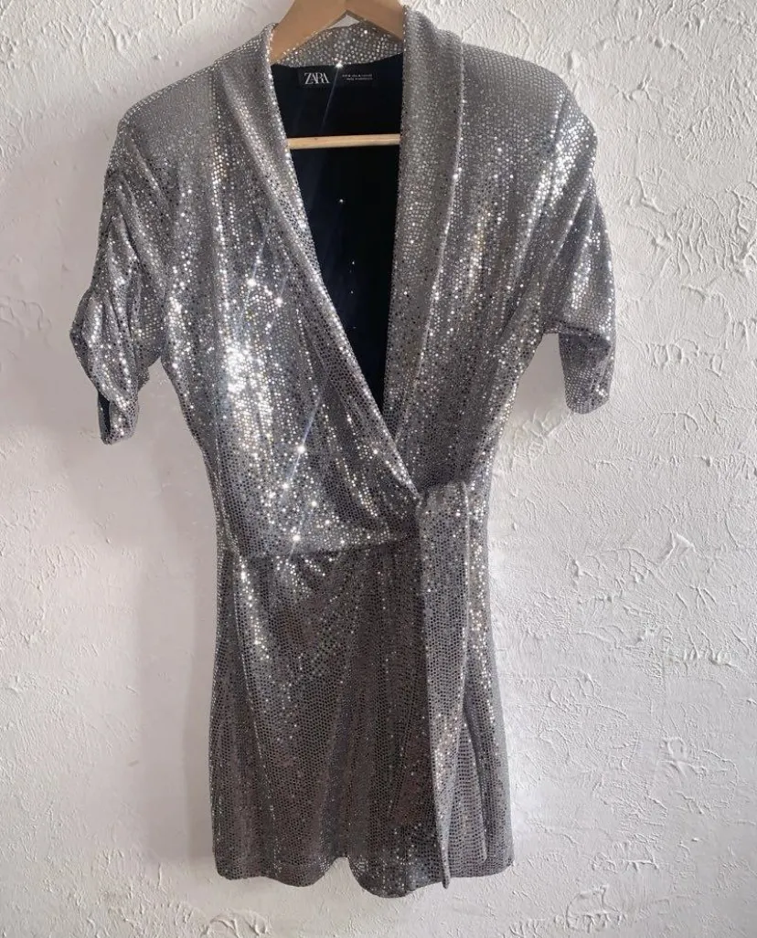 Mono plateado con lentejuelas y lazo en la cintura. Mangas cortas con fruncido.
Se uso 1 vez . igual a nuevo
