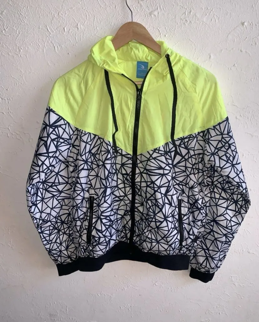 Campera deportiva con capucha, cierre al frente y puños elastizados. Diseño combinado con parte superior en color verde flúo y estampa geométrica en blanco y negro en la parte inferior y mangas.