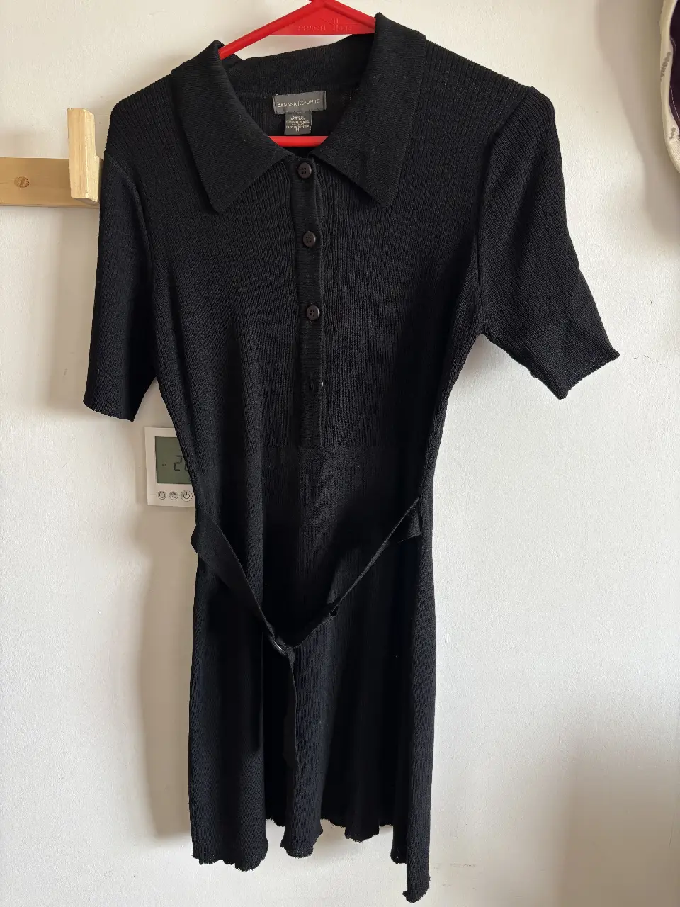 Vestido midi negro de punto con cuello tipo polo y mangas cortas. Incluye cinturón para ajustar la cintura. Ideal para un look elegante y versátil.