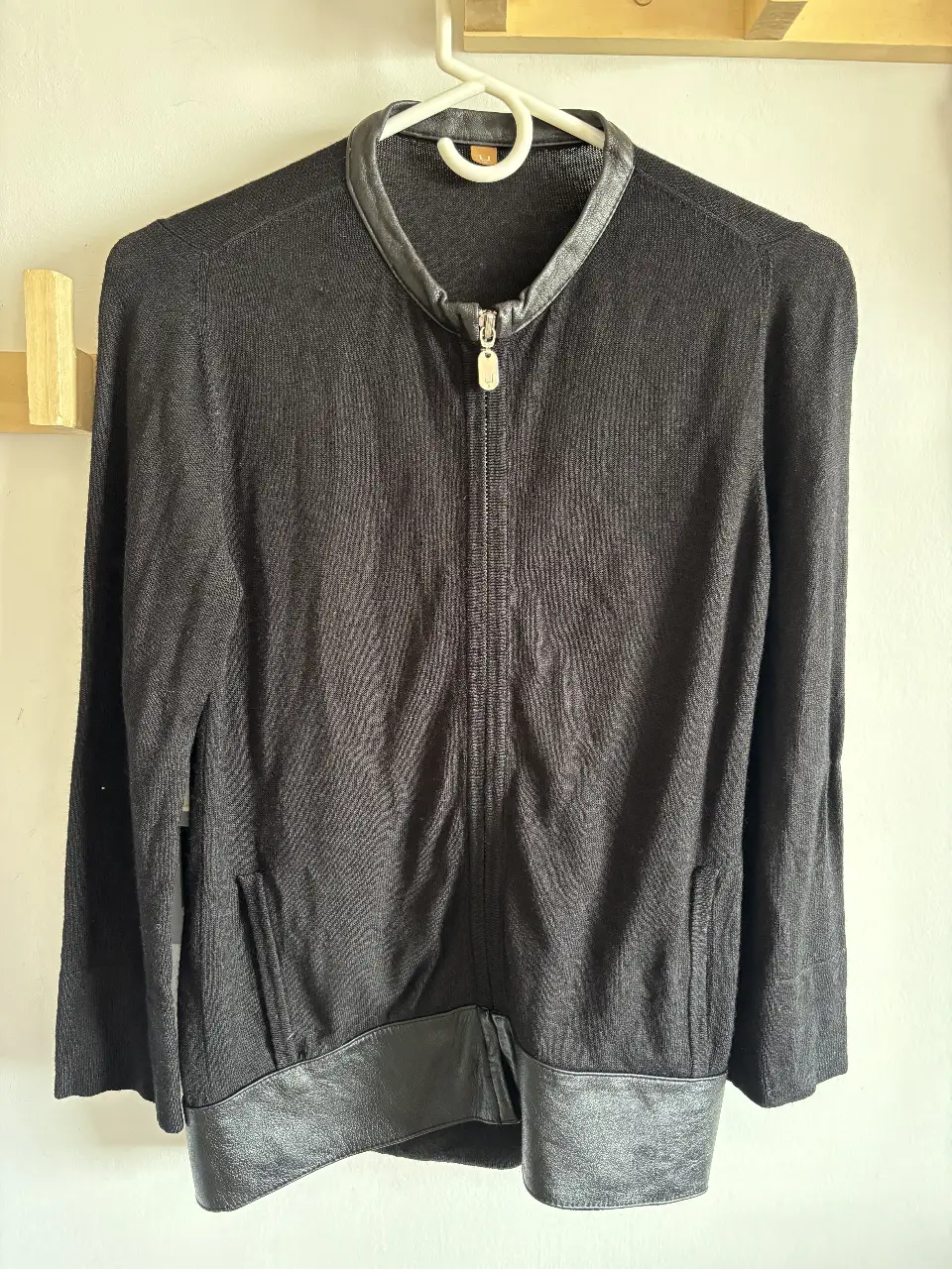 Cardigan negro con cuello y detalles en cuero. Cierre frontal y bolsillos. Ideal para un look elegante y versátil.
