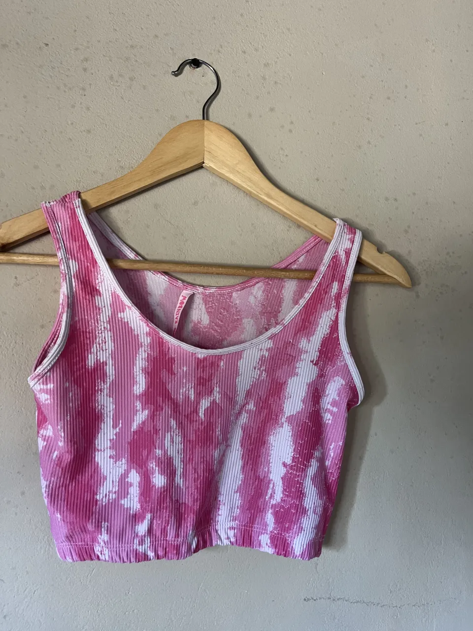 Musculosa deportiva con estampa tie-dye en tonos de rosa y blanco. Posee detalles de costura blanca en los bordes.