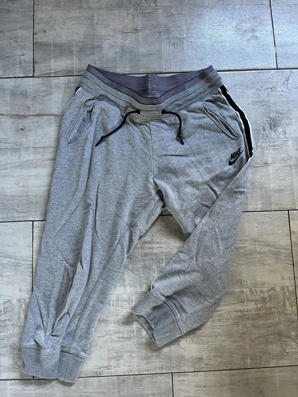 Pantalón de jogging gris con franja lateral blanca y negra. Cintura elastizada con cordón.