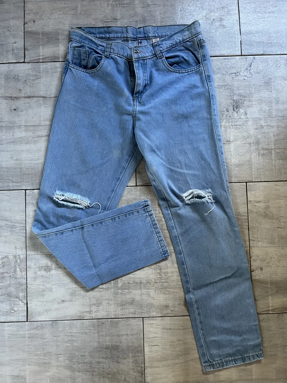 Jean de tiro alto con roturas en ambas rodillas. Lavado celeste.