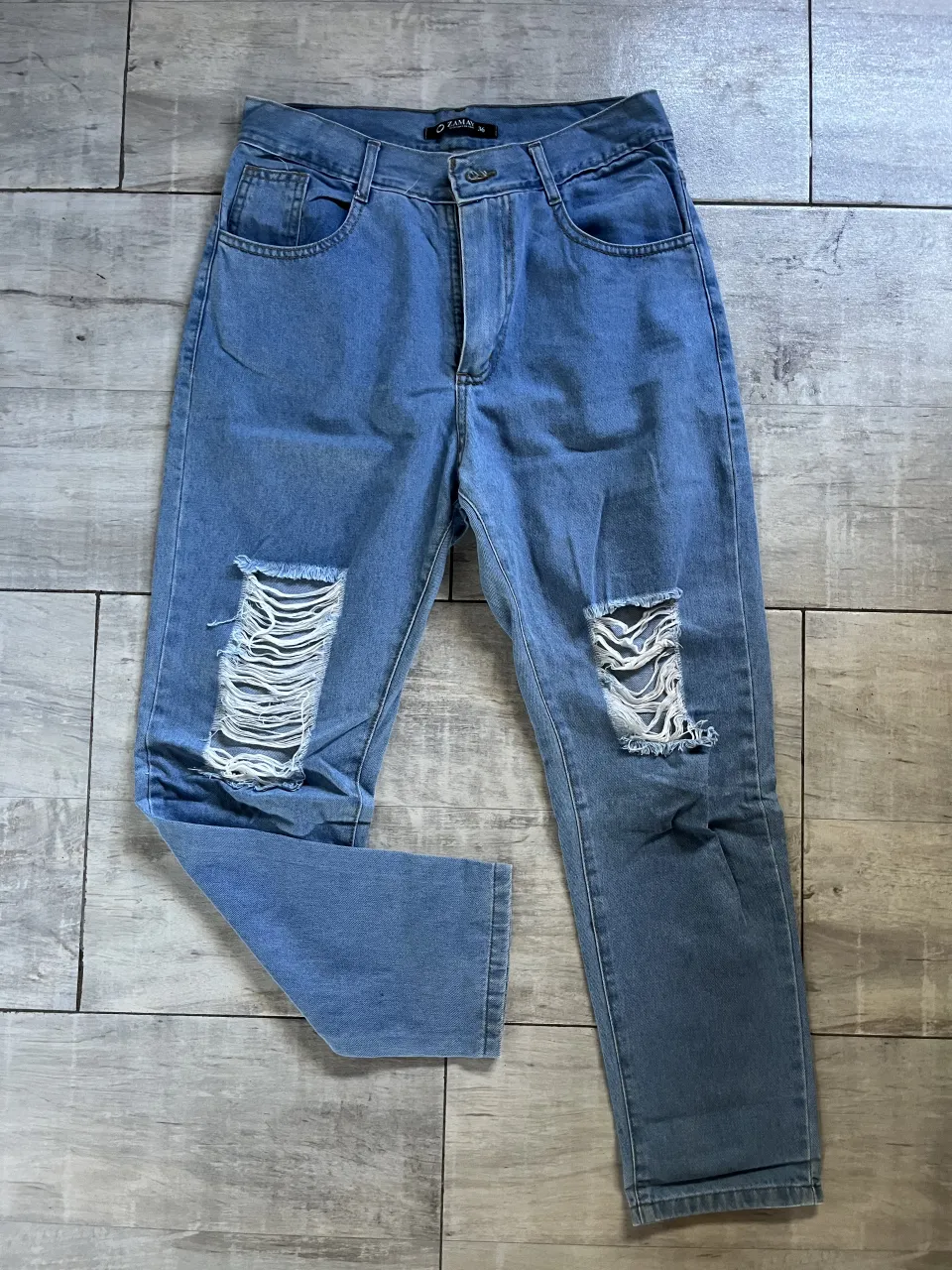 Jeans de denim celeste con roturas en ambas piernas.