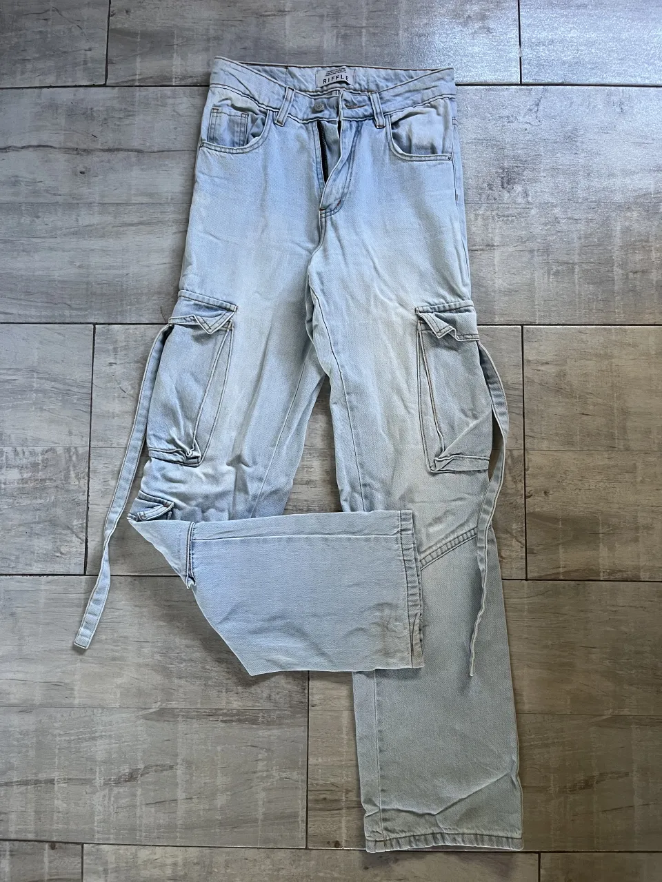 Jean cargo de tiro alto con bolsillos laterales y tiras para ajustar. Lavado celeste claro.