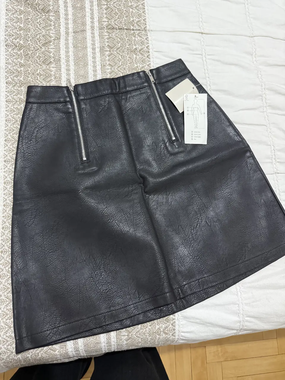 Minifalda de cuero sintético negra con cierre frontal y detalles de diseño. Ideal para un look moderno y audaz.