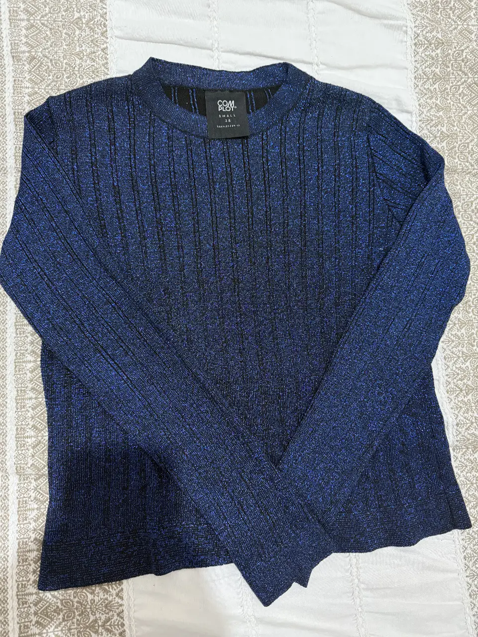 Sweater brilloso en color azul con detalles en negro. Ideal para un look elegante y abrigado.