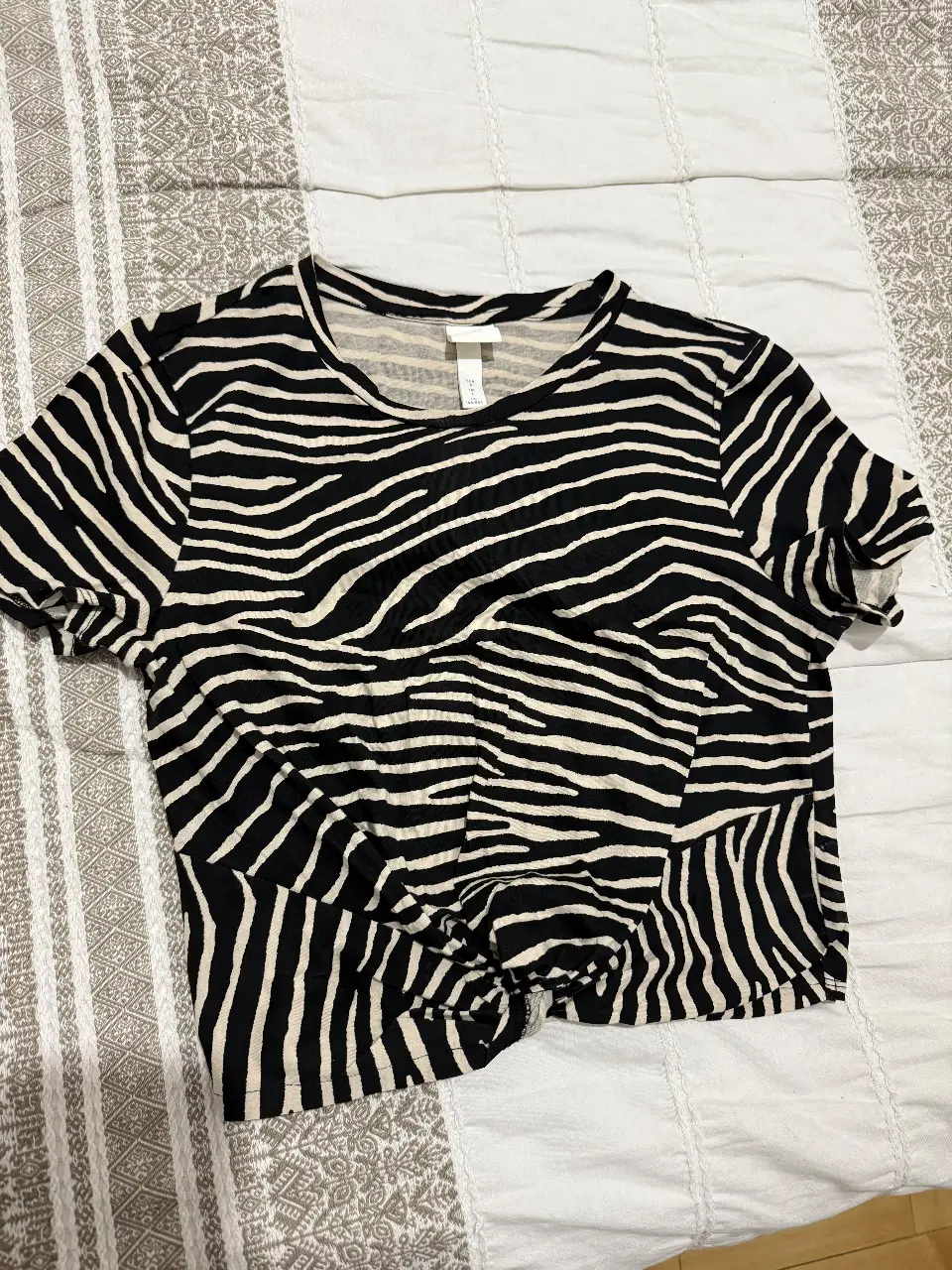 Remera de mujer corta con estampado de cebra en blanco y negro. Diseño con nudo en la parte delantera, ideal para un look casual y moderno.