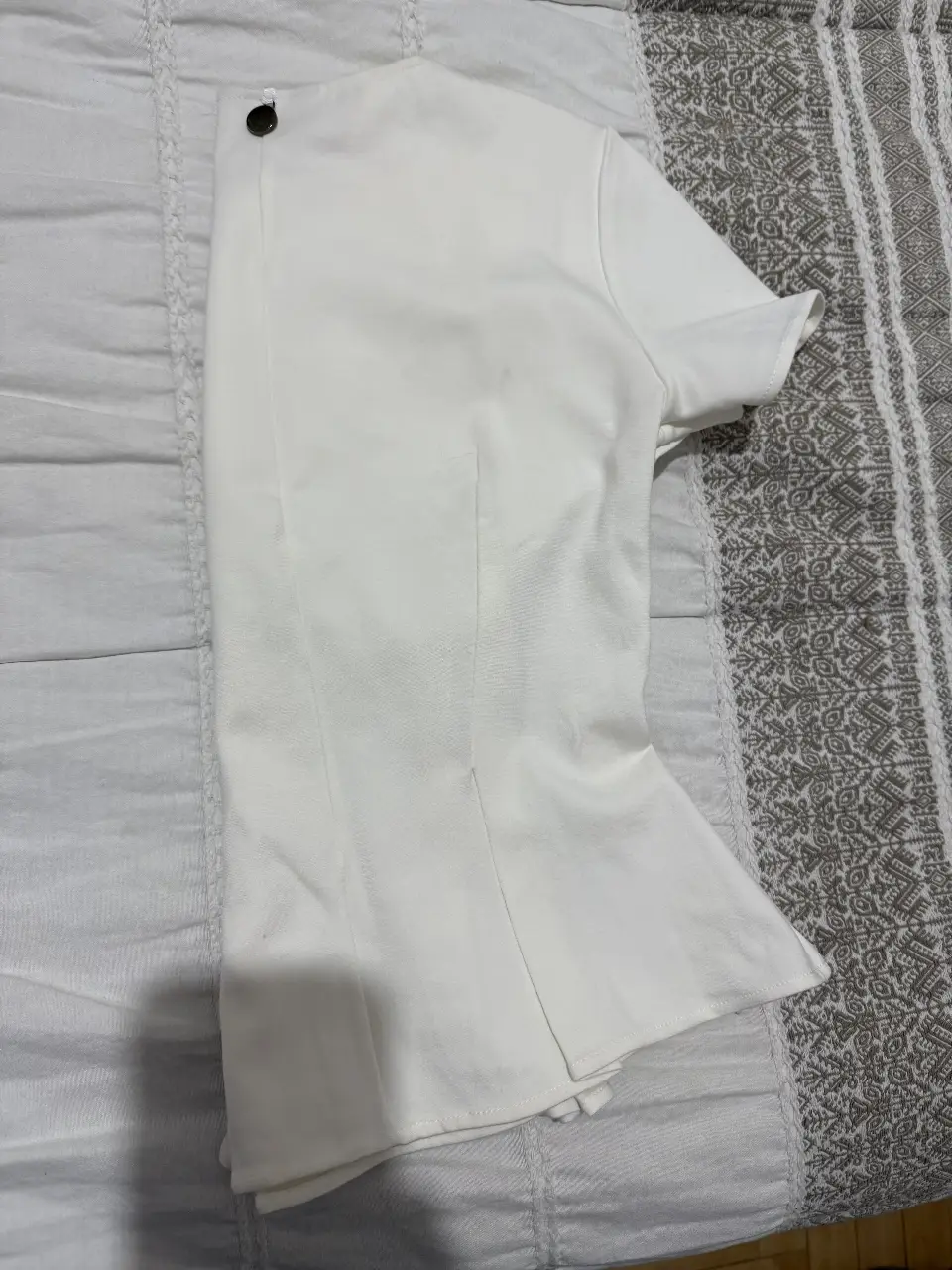 Blusa blanca de manga corta con detalle de botón en el cuello. Ideal para un look elegante y sofisticado.
