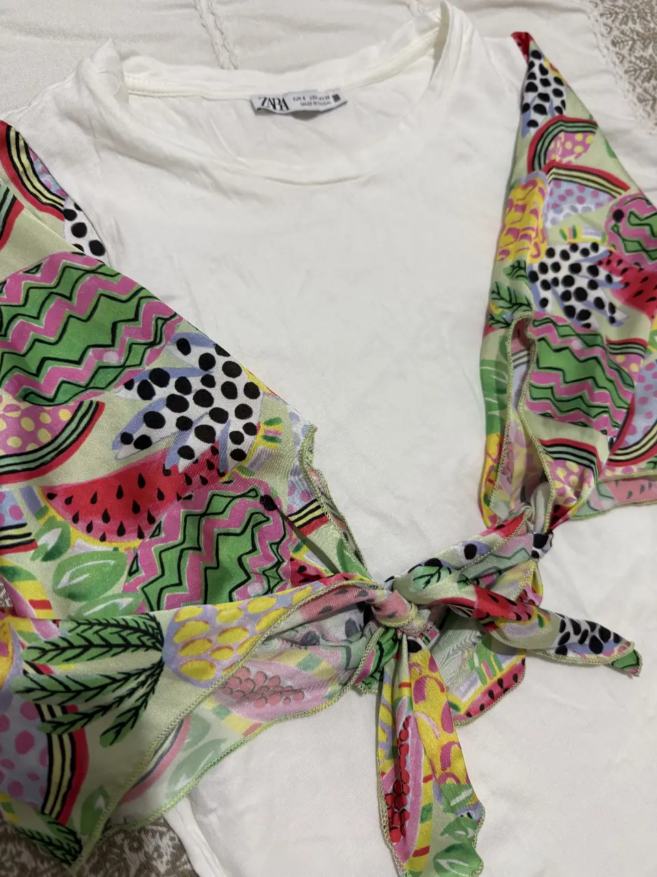Remera blanca con mangas cortas estampadas con diseño de frutas y formas abstractas. Ideal para un look fresco y moderno.