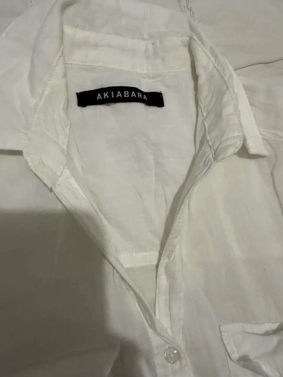 Camisa blanca de manga larga con dos bolsillos delanteros. Ideal para un look casual y fresco.