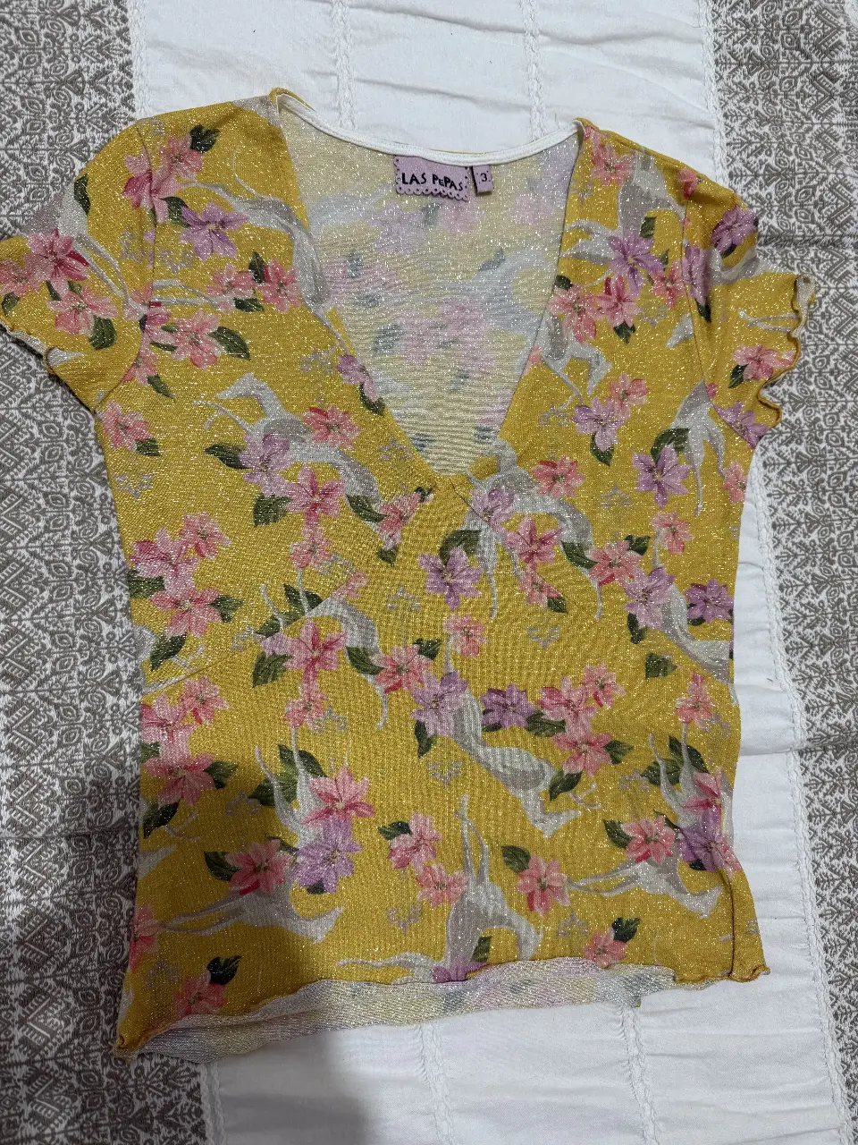 Blusa amarilla con estampado floral en tonos rosas y lilas. Corte en V y mangas cortas con volados. Ideal para un look fresco y femenino.