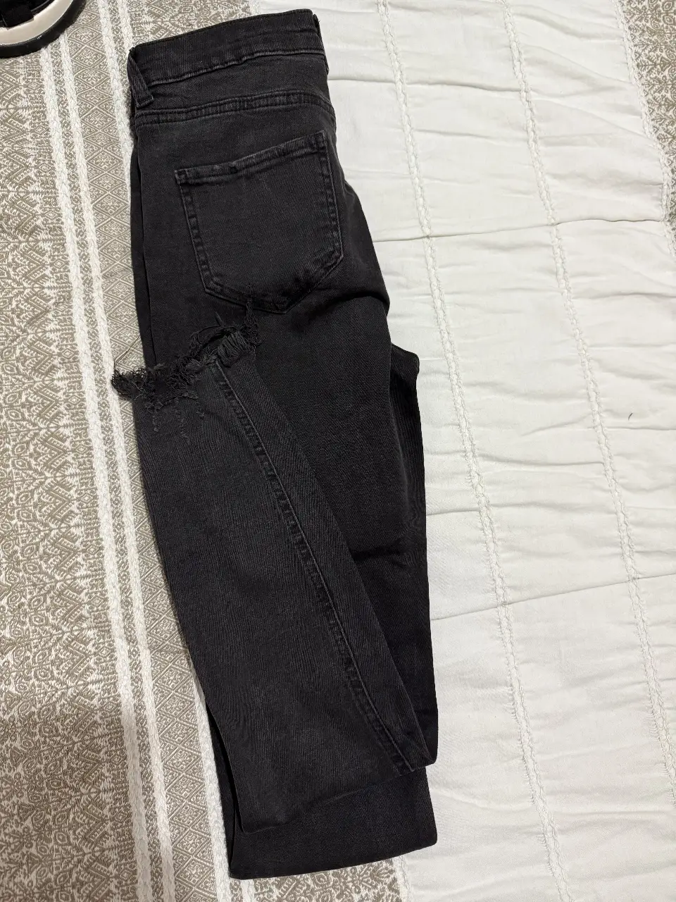 Jeans de mujer negros con roturas en las rodillas y en el borde inferior. Tiro bajo. Ideal para un look casual y moderno.