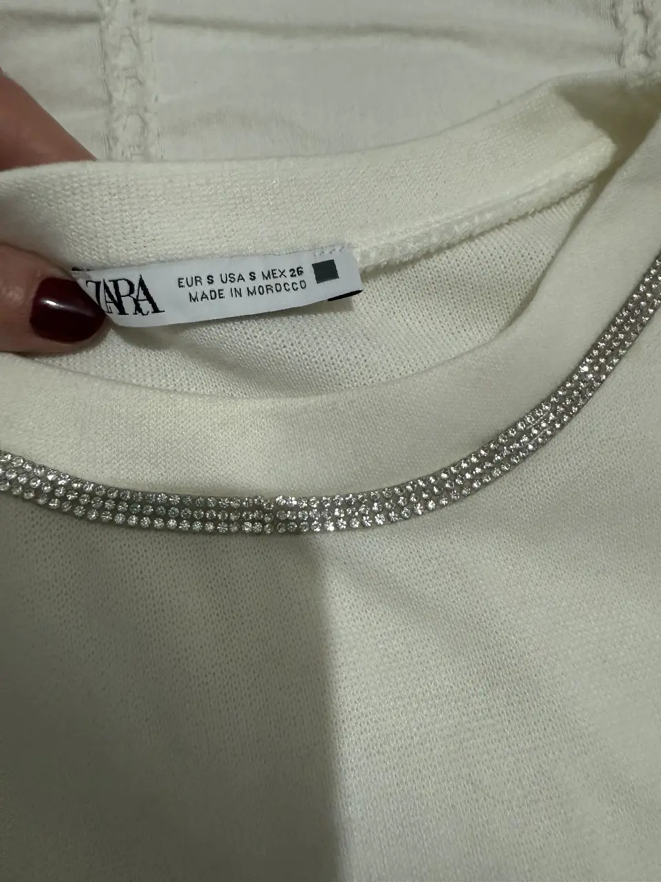 Sweater de cuello redondo con detalle de brillos en el cuello. Ideal para un look elegante y sofisticado. con algunas manchas 