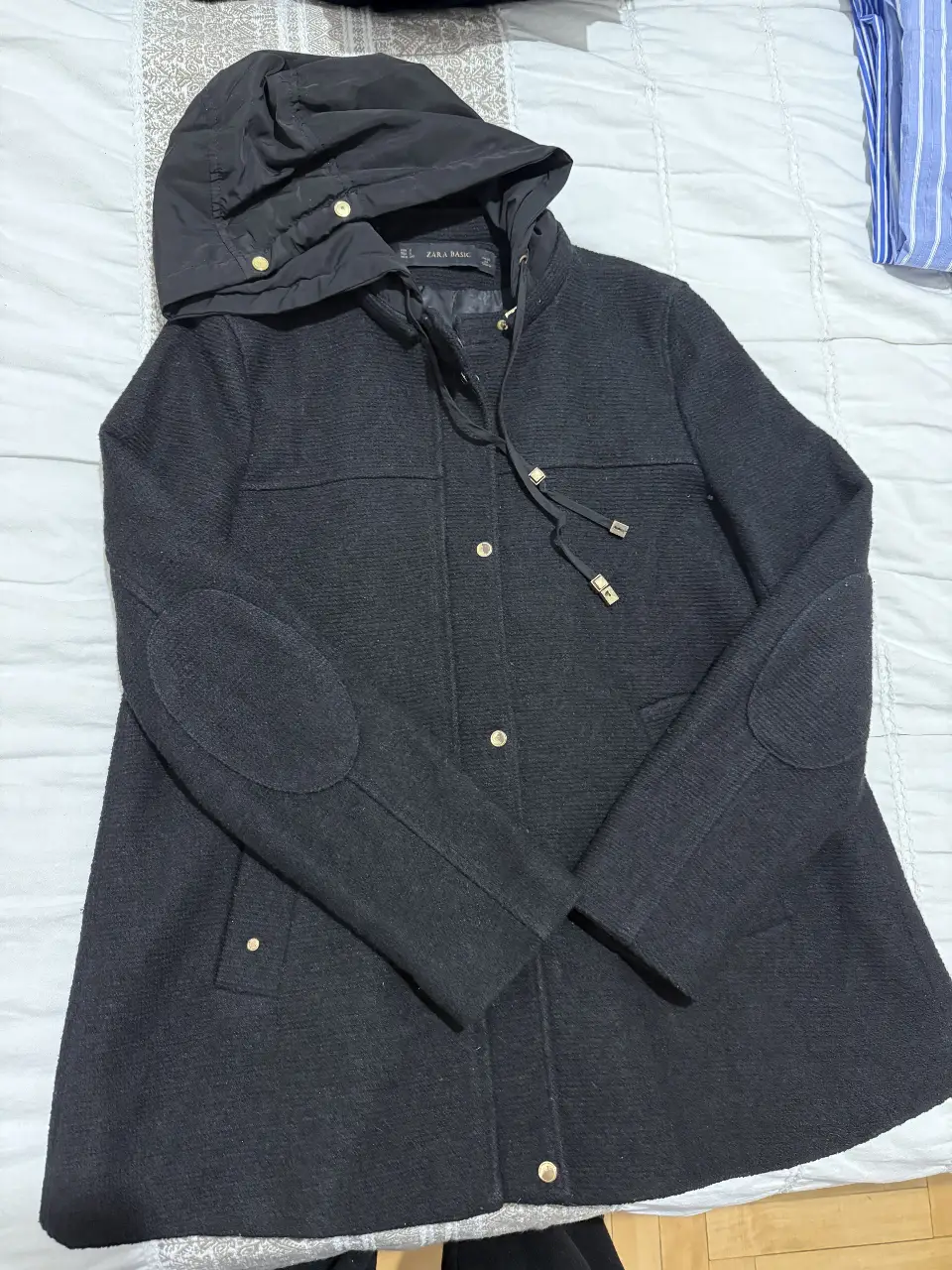 Tapado negro Zara de paño con capucha desmontable, detalles dorados en botones y cierres. Ideal para el invierno, estilo casual y elegante.