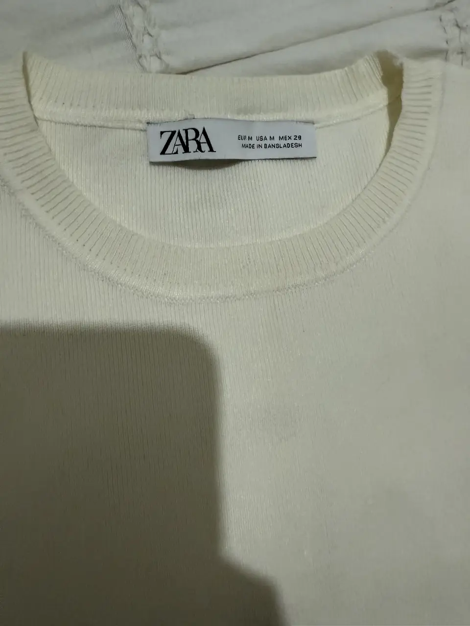 Sweater de cuello redondo color blanco, corto de la marca Zara. Ideal para un look casual y cómodo. tiene una pequeña mancha en el frente.