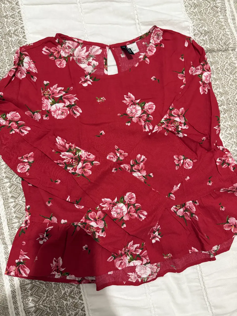 Blusa roja con estampado floral en tonos rosas y blancos. Diseño con volados en la parte inferior. Ideal para un look femenino y fresco.