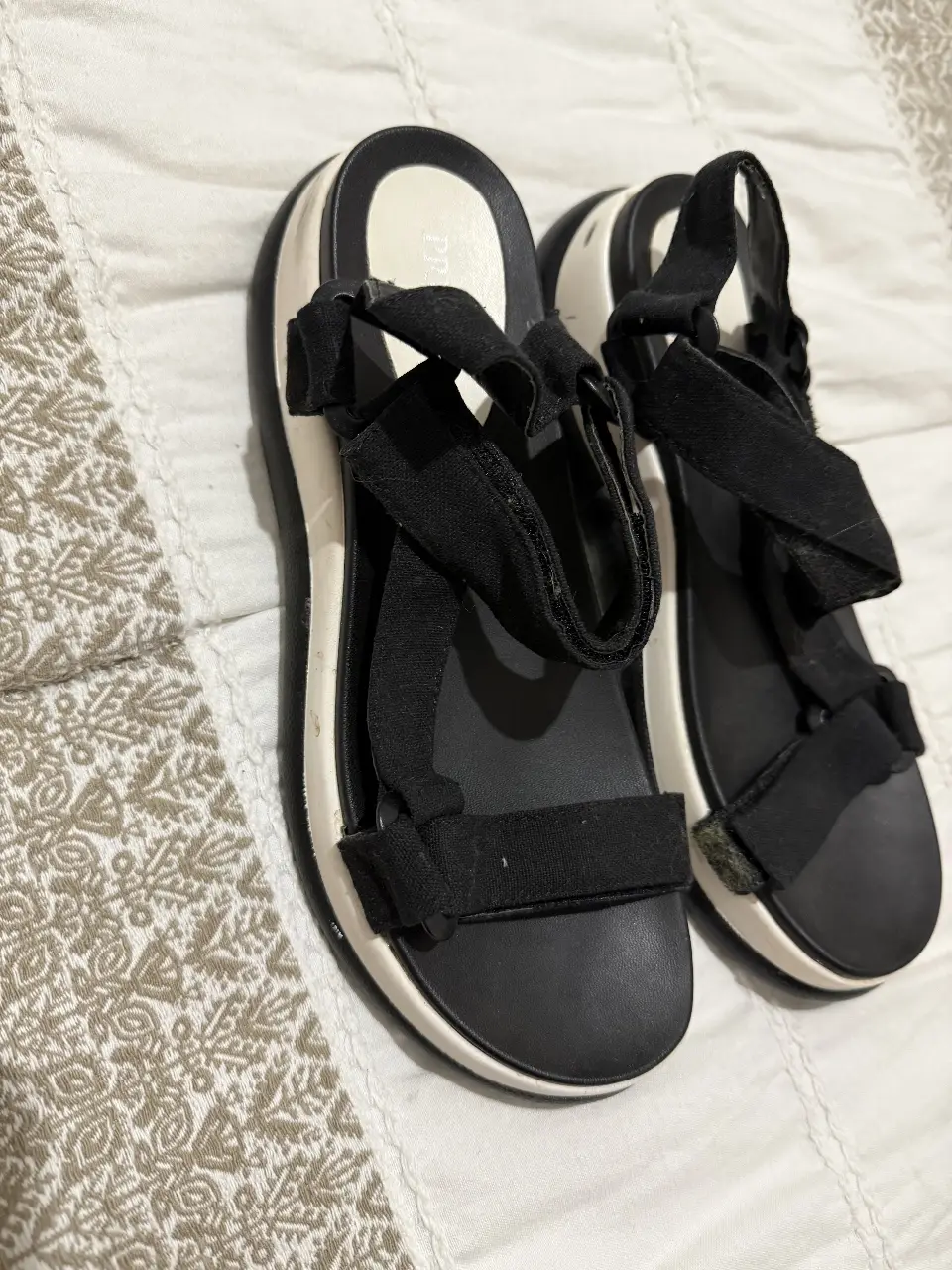 Sandalias de plastico negras con base blanca y tiras ajustables. Ideales para un look casual y cómodo.