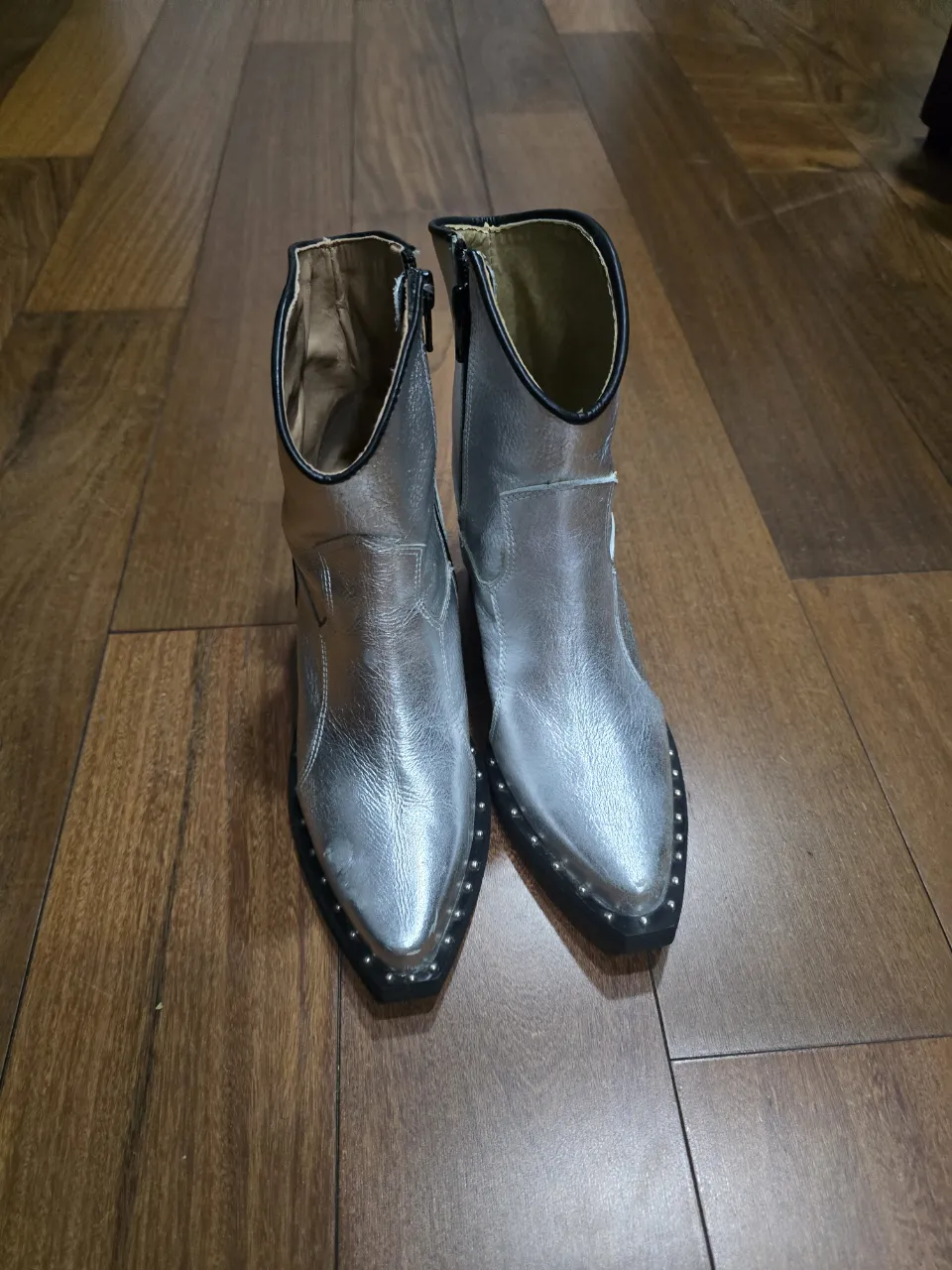 Botitas texanas plateadas con tachas en la punta y taco grueso. Cierre lateral para facilitar el calce.