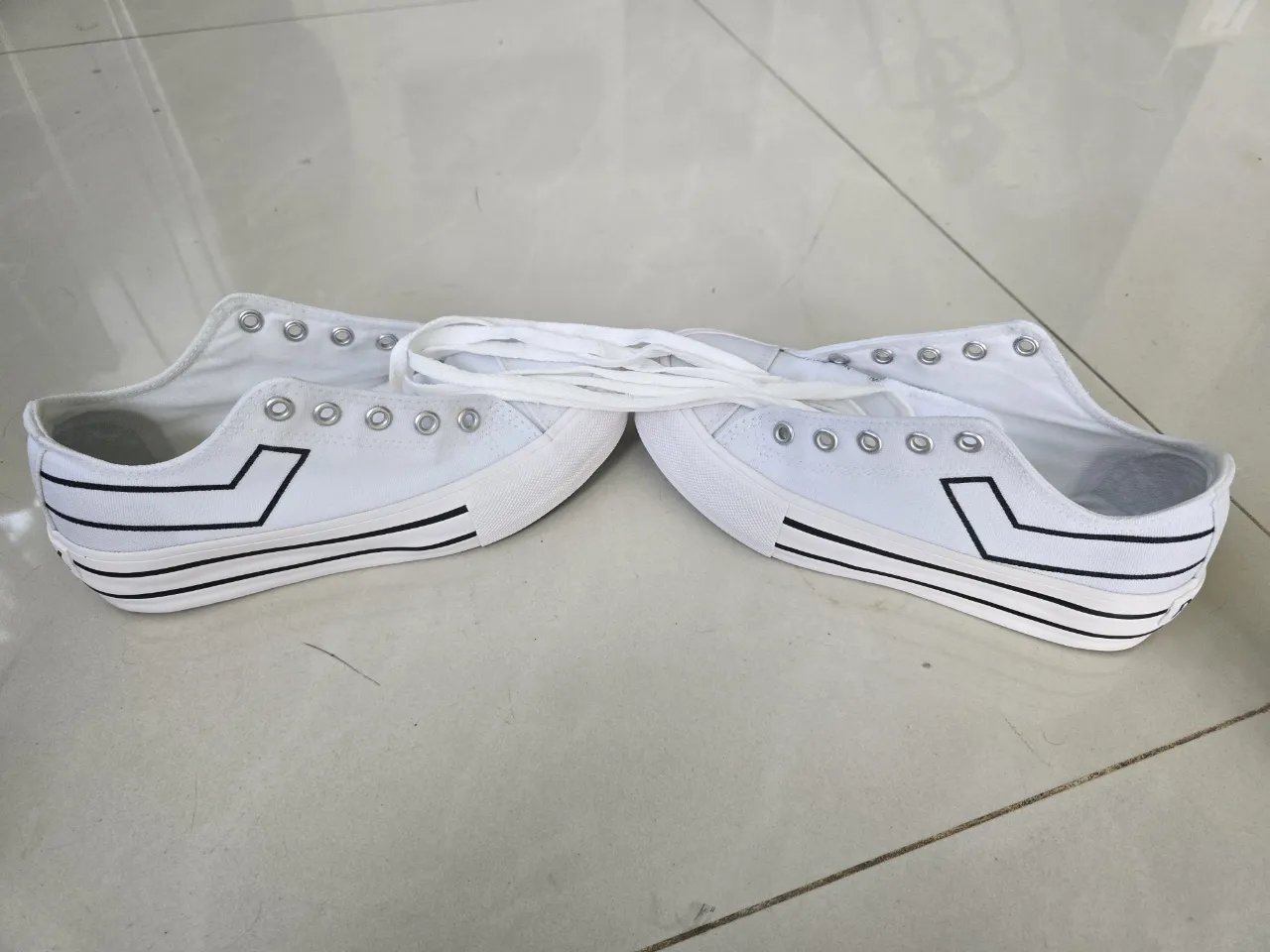 Zapatillas impecables con plataforma de 
lona blancas con cordones. Tienen detalles de líneas negras en los laterales y en la suela. La marca 'PONY' se lee en la parte trasera de la suela.