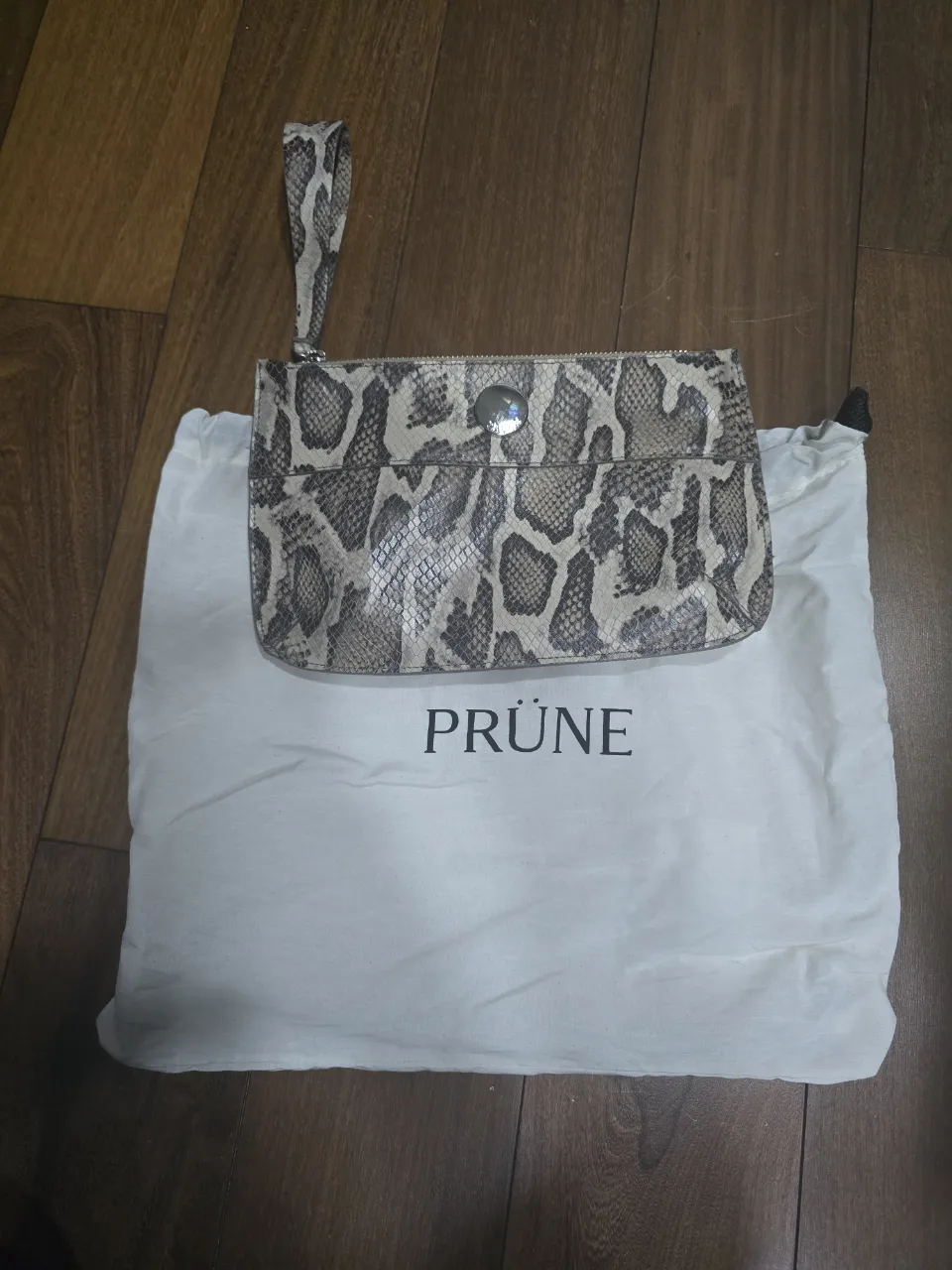 Cartera de mano con estampa de serpiente y correa.