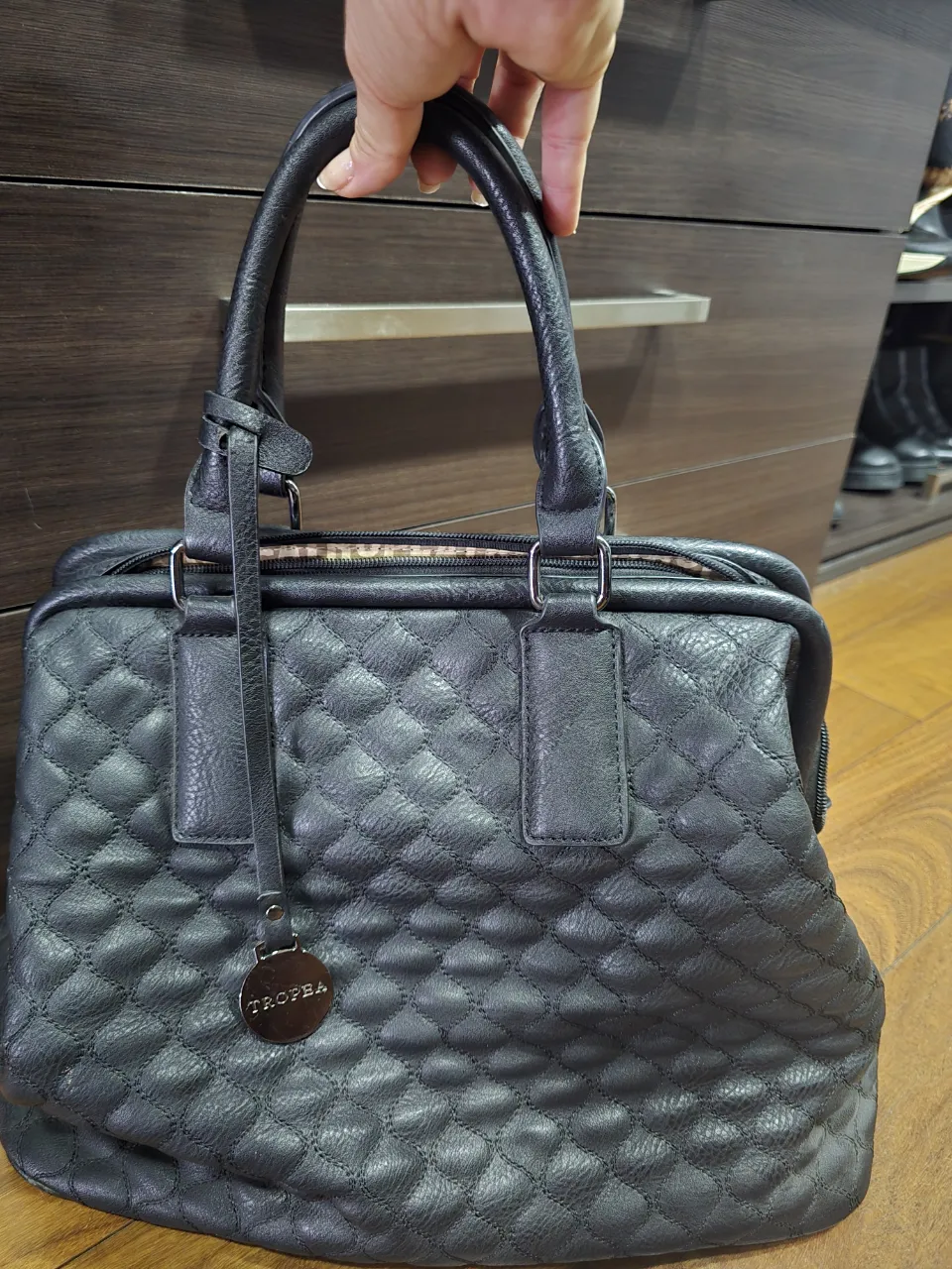 Bolso negro matelaseado con detalles en cuero. Interior forrado con estampa de la marca. Cierre principal y bolsillos internos. Ideal para el día a día o para un look más arreglado.