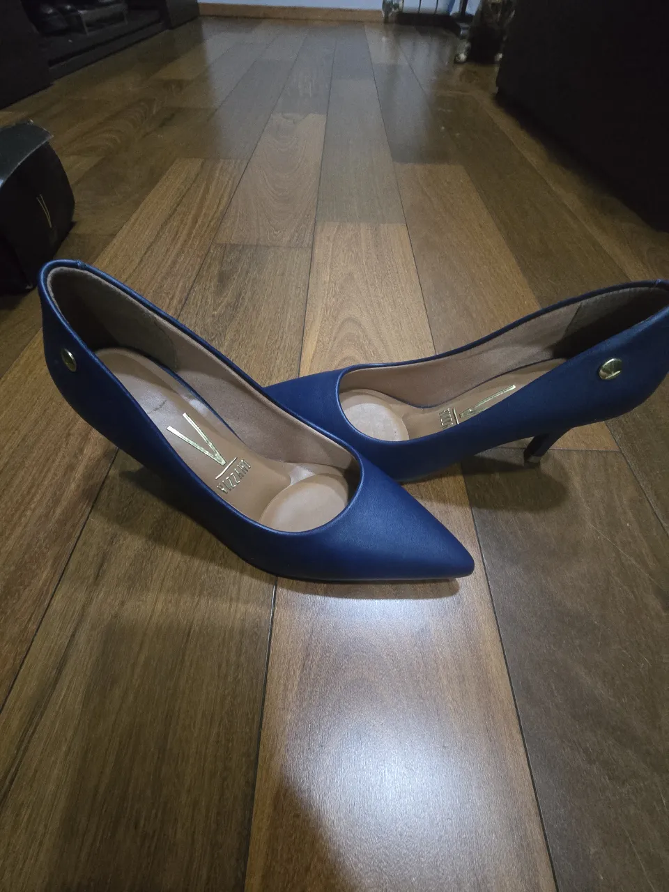 Zapatos de taco aguja color azul marino, con punta fina y detalle metálico dorado en el talón. Ideales para un look elegante y sofisticado.