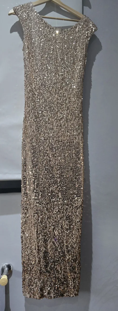 Vestido largo de fiesta con lentejuelas brillantes, ideal para deslumbrar en cualquier evento especial. Su diseño elegante y sofisticado lo convierte en la opción perfecta para celebraciones y galas.