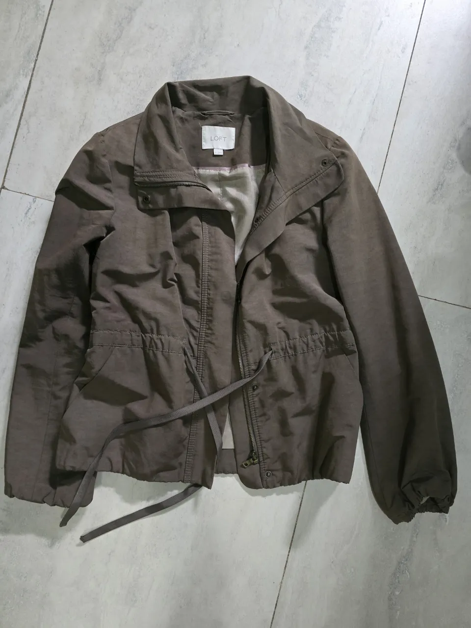 Campera de color marrón con cordón ajustable en la cintura y cierre al frente. Tiene cuello mao y bolsillos laterales. Impecable, traída de USA