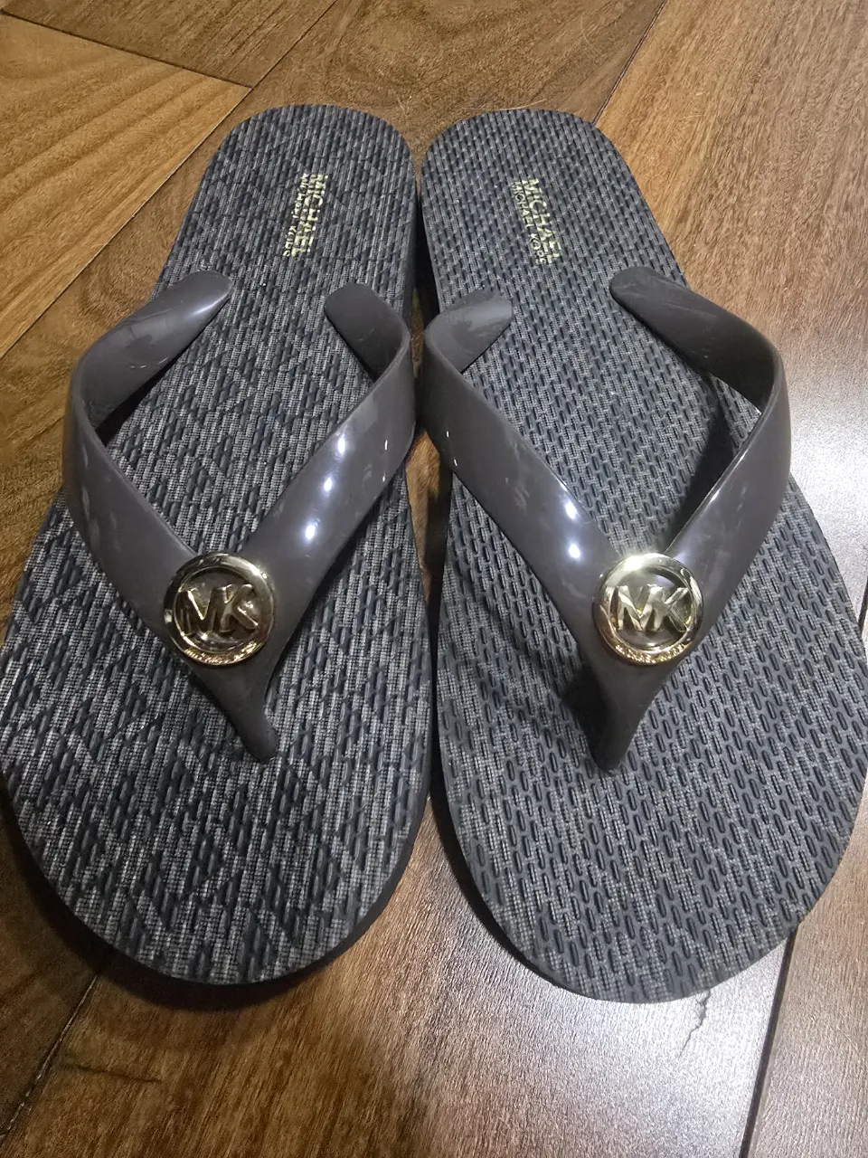 Ojotas Michael Kors grises con logo dorado. Perfectas para un look casual de verano o para la playa.
