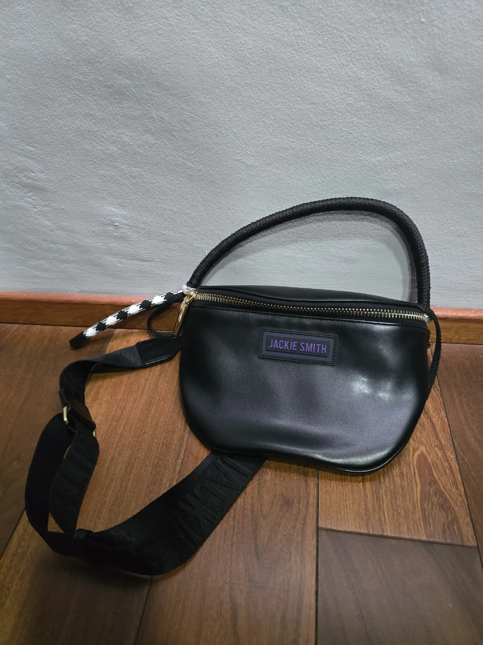 Riñonera negra de cuero sintético, con correa ajustable y logo de la marca en la parte frontal. Cierre principal con detalle de tirador.