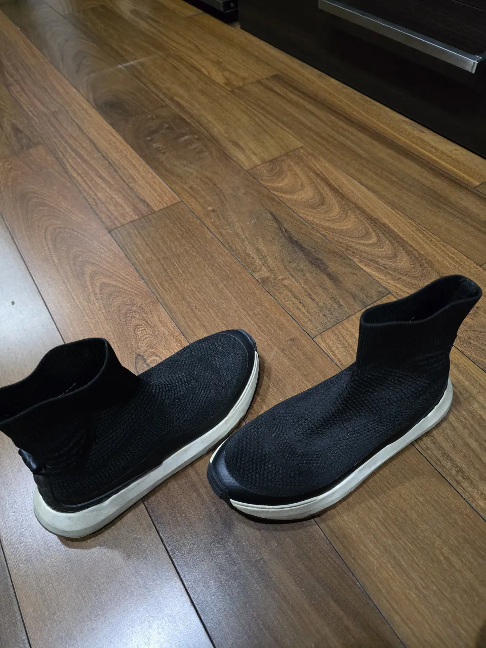 Zapatillas urbanas negras, estilo botita, con suela blanca. Perfectas para un look casual y moderno.